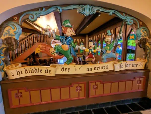 Wood carving depicting Pinocchio dancing with friends at Pinocchio Village Haus in Magic Kingdom